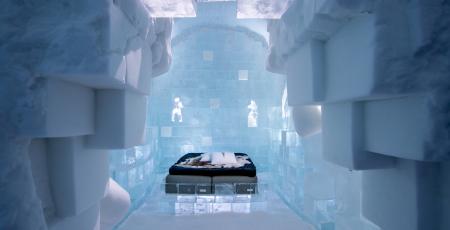 overview of art suite made of ice and snow with double bed with reindeer hides