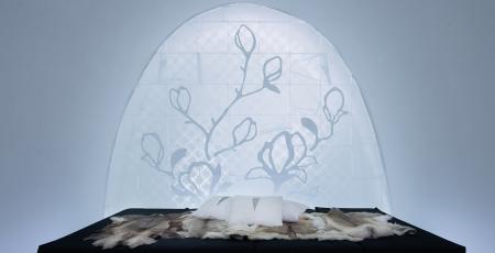 a bed covered with reindeer hides surrounded by beautiful ice art at icehotel