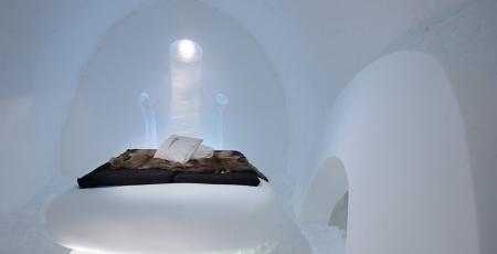 A bed of snow in the shape of the core of an apple in a room of snow at icehotel