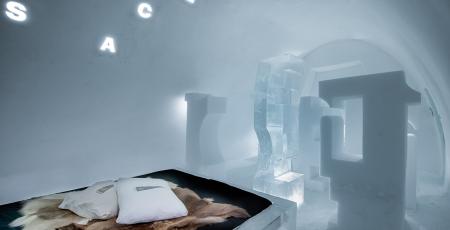 double bed with reindeer hides in a room of ice in Icehotel