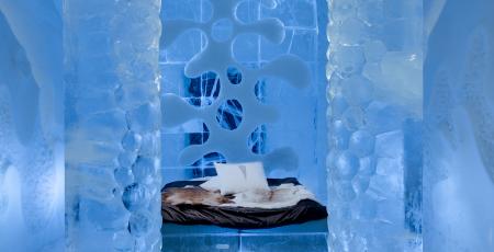 bedroom with bed surrounded by an arch of ice in deluxe suite made of snow and ice