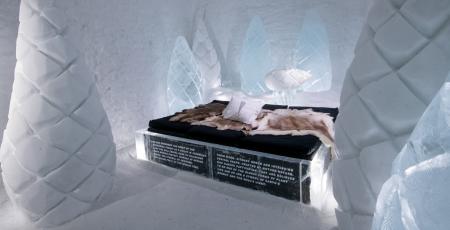 En säng i en issvit omringas av stora kottar av snö