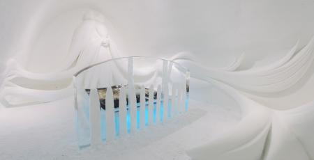 bed surrounded by a dog with long hair made of snow at Icehotel