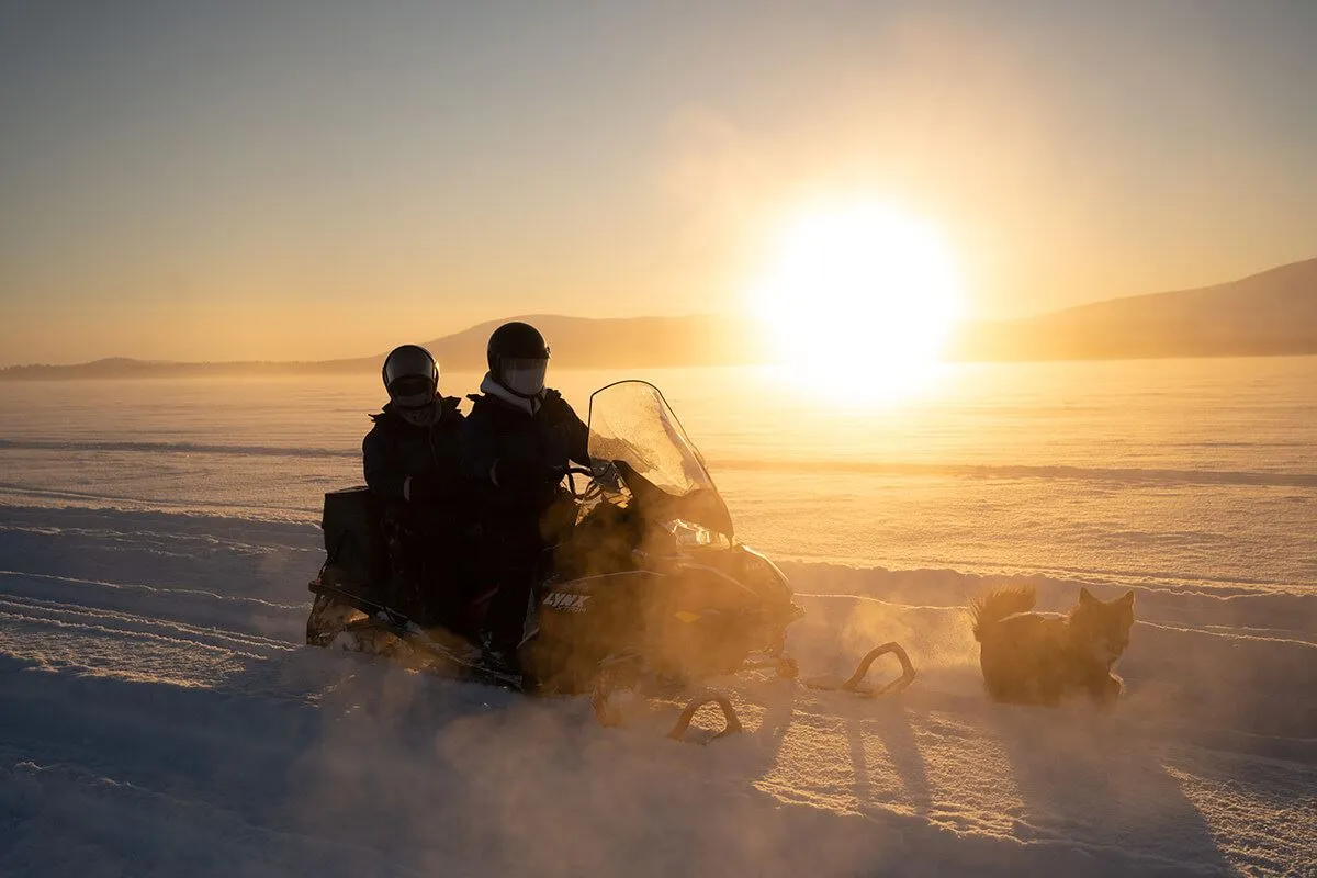 Snowmobile driving in the sunset